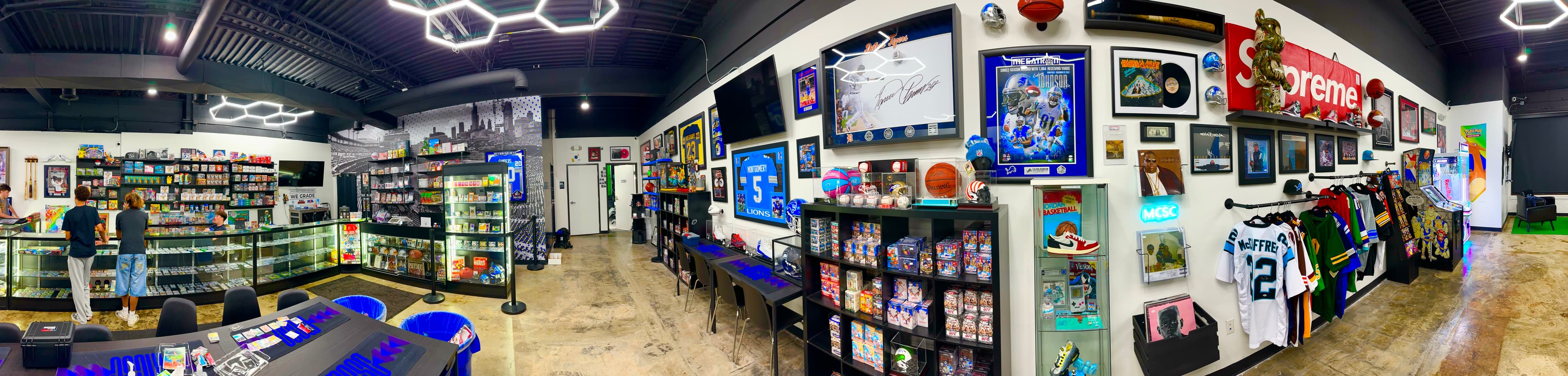 Wide view inside Motor City Sports Cards, with display cases, card shelves, jerseys, and collectibles
